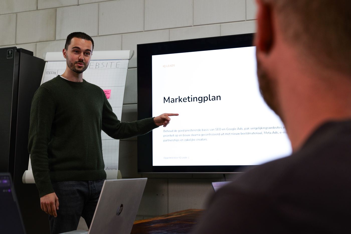 Een specialist van IQ Leads presenteert een marketingplan op een scherm